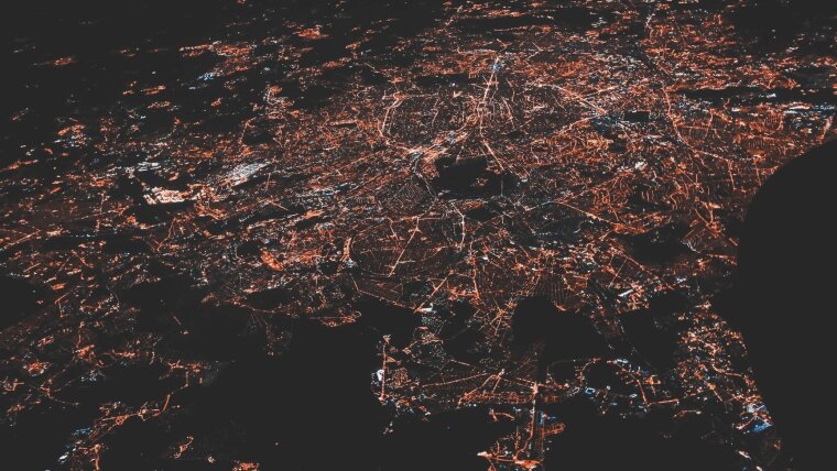 Nächtliche Luftaufnahme einer Stadt mit beleuchtetem Straßennetz