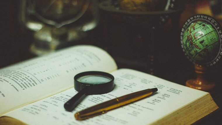 open book with a magnifier and a pen